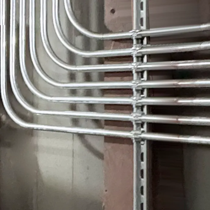 Seven metal conduit runs bent in matching curves, turning along a wall and held level on a metal strut